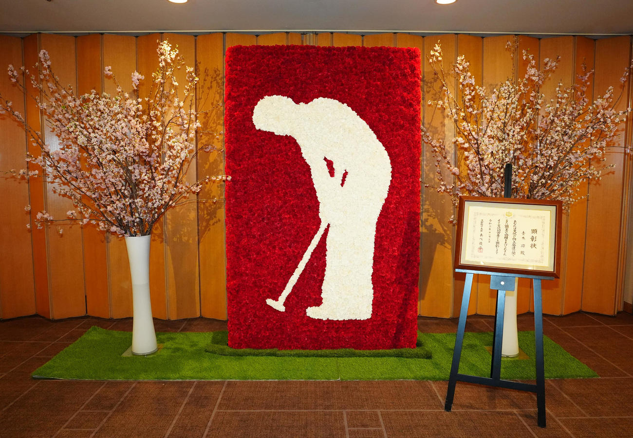 文化功労者顕彰を祝う会で展示されるカーネーションの花でつくられたモニュメントと青木の文化功労者顕彰状（撮影・江口和貴）