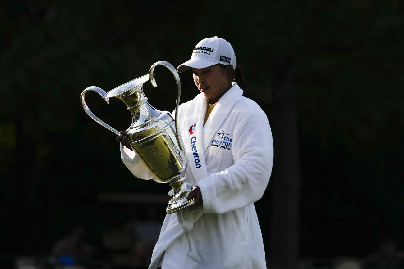 シェブロン選手権で優勝し、池へのウイニングダイブ後、チャンピオンシップ・ローブを着てトロフィーを掲げる西郷真央（AP）