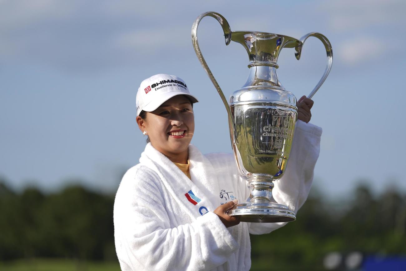 シェブロン選手権で優勝し、池へのウイニングダイブ後、チャンピオンシップ・ローブを着てトロフィーを掲げる西郷真央（AP）