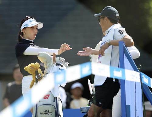 14番、キャディに菓子を渡す脇元（左）（撮影・河田真司）