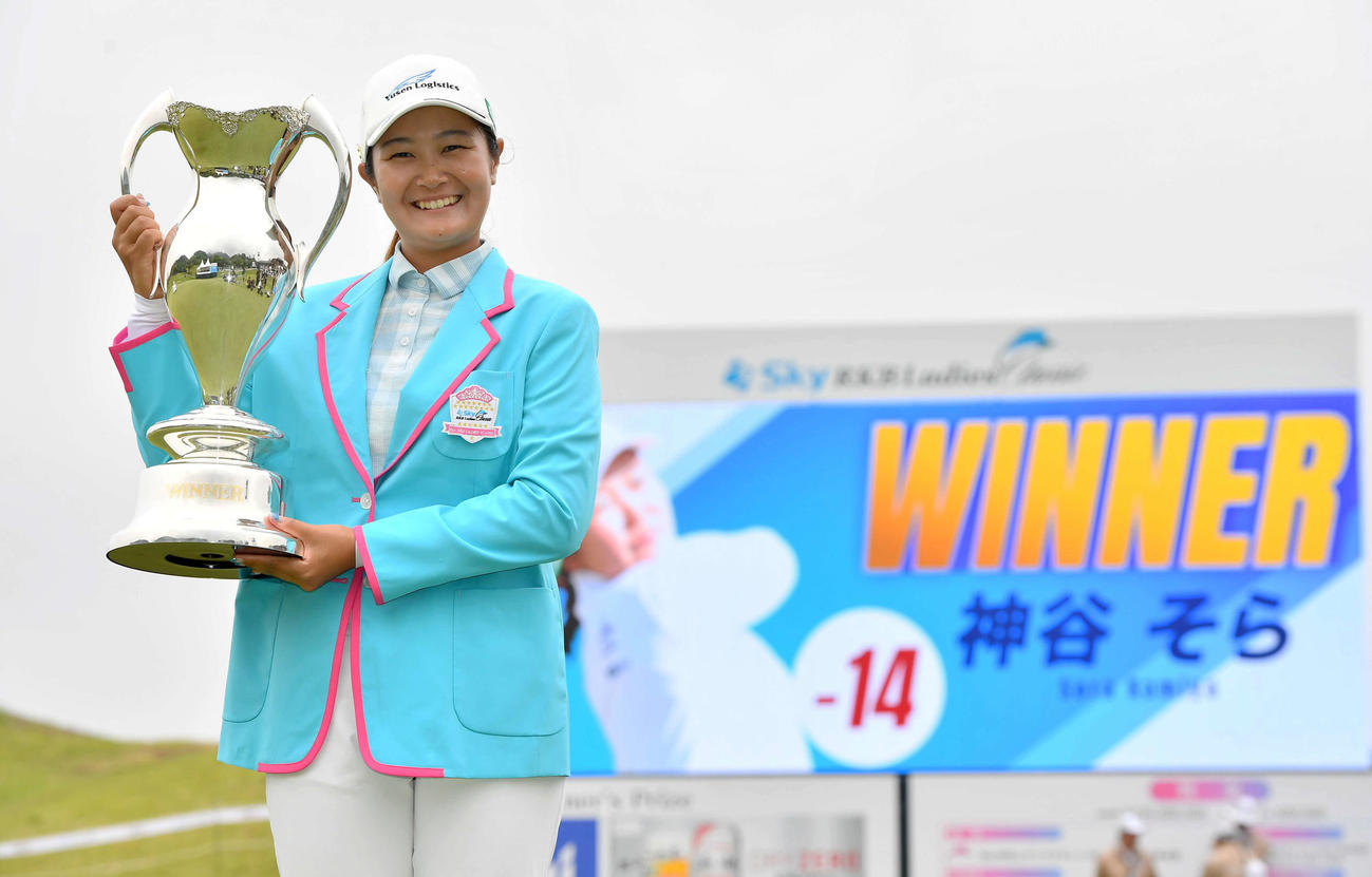 通算14アンダーで優勝し、笑顔で優勝カップを掲げる神谷（撮影・岩下翔太）