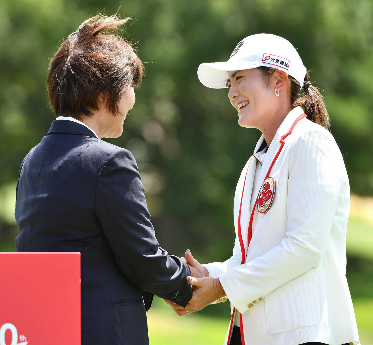 通算17アンダーで優勝した渡辺彩香（右）は、表彰式後にJLPGA小林浩美会長と笑顔で握手を交わす（撮影・岩下翔太）