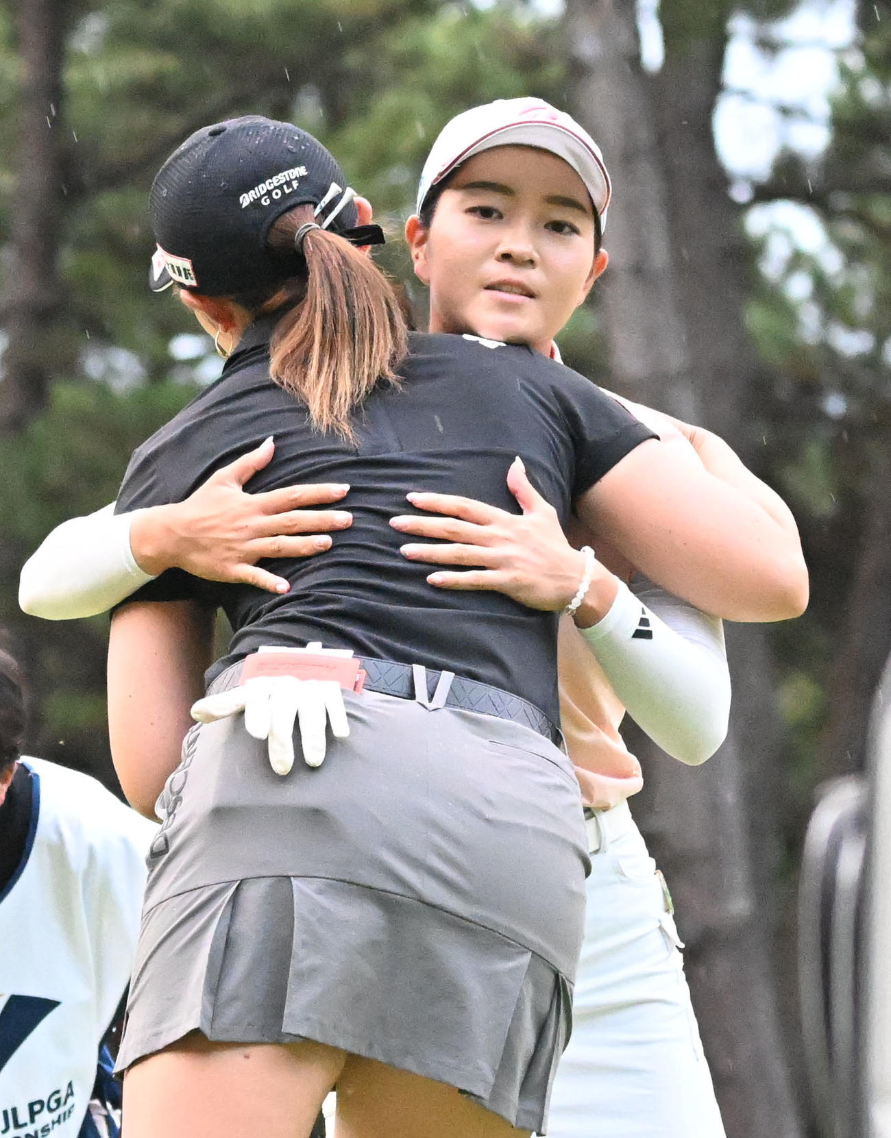 ソニー日本女子プロゴルフ選手権大会第2日、通算10アンダーで単独首位でホールアウトし、同組の渡辺彩香（手前）と健闘をたたえ合う佐藤心結（撮影・千葉一成）