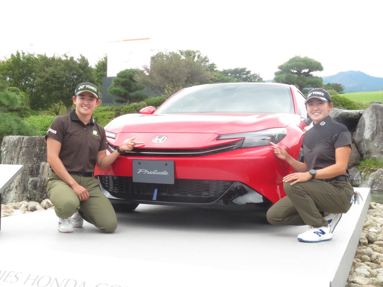 大会優勝者の副賞として展示されたホンダの乗用車の前で、記念撮影に臨んだ姉明愛と妹千怜の岩井姉妹