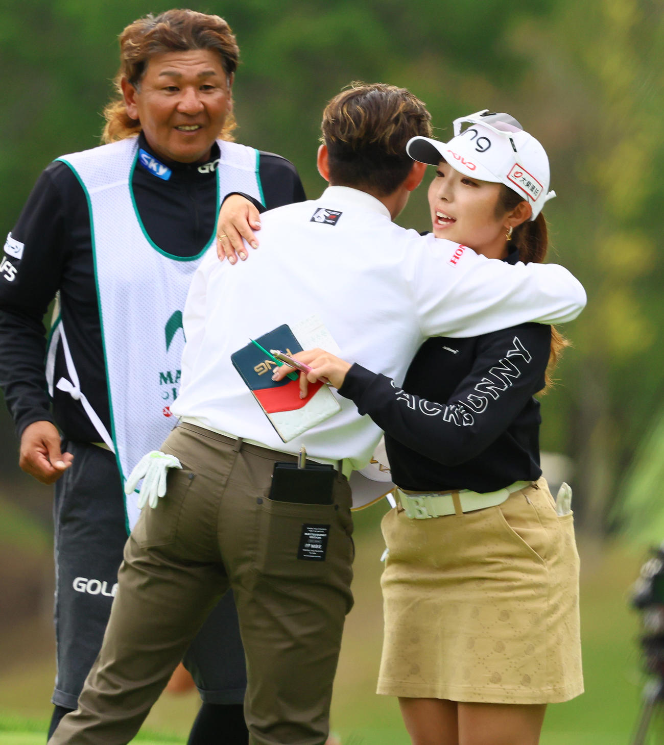 ホールアウトし岩井明（手前）とハグする佐久間（撮影・上山淳一）