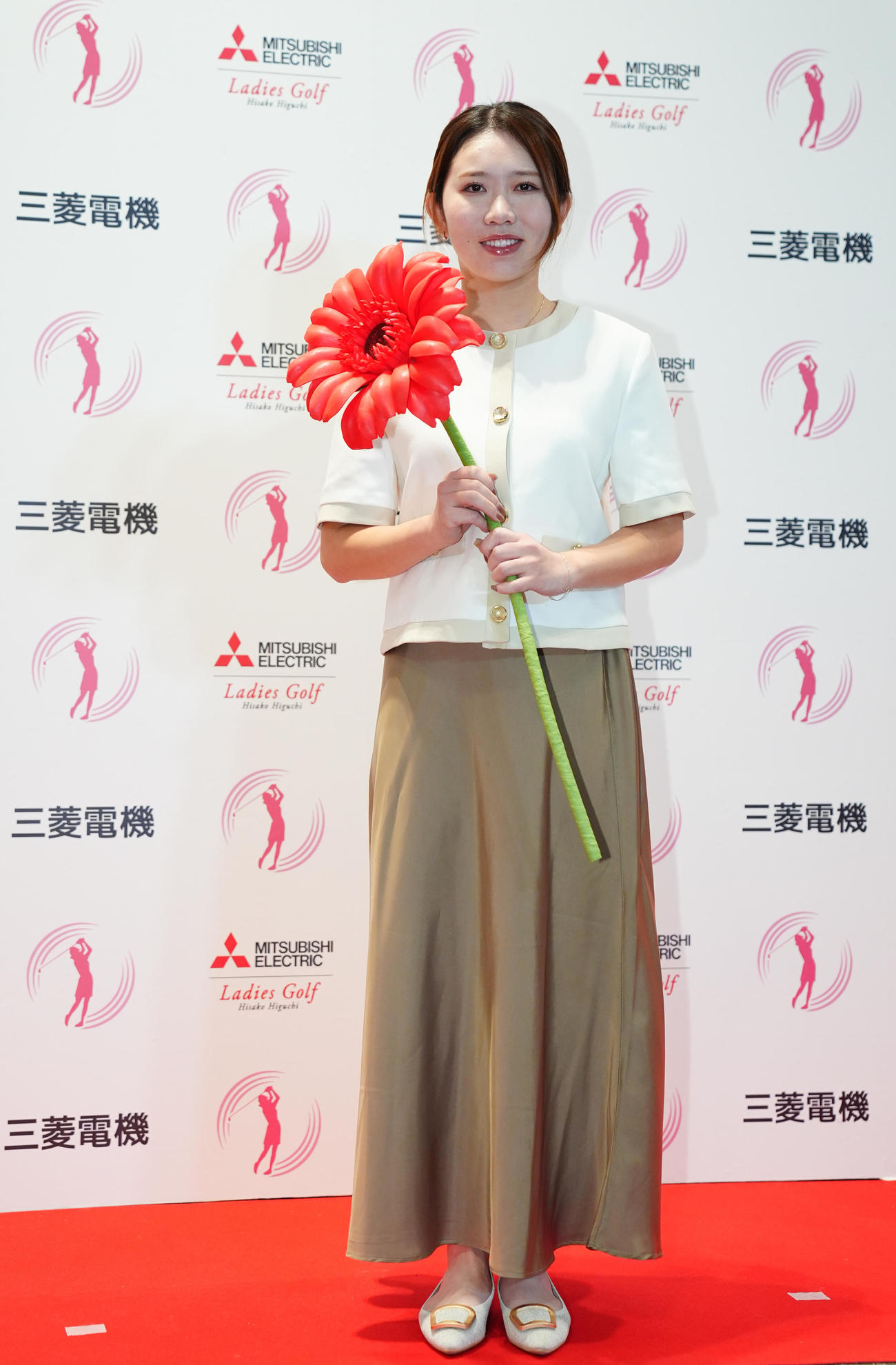 ガーベラを手に写真に納まる内田（撮影・垰建太）