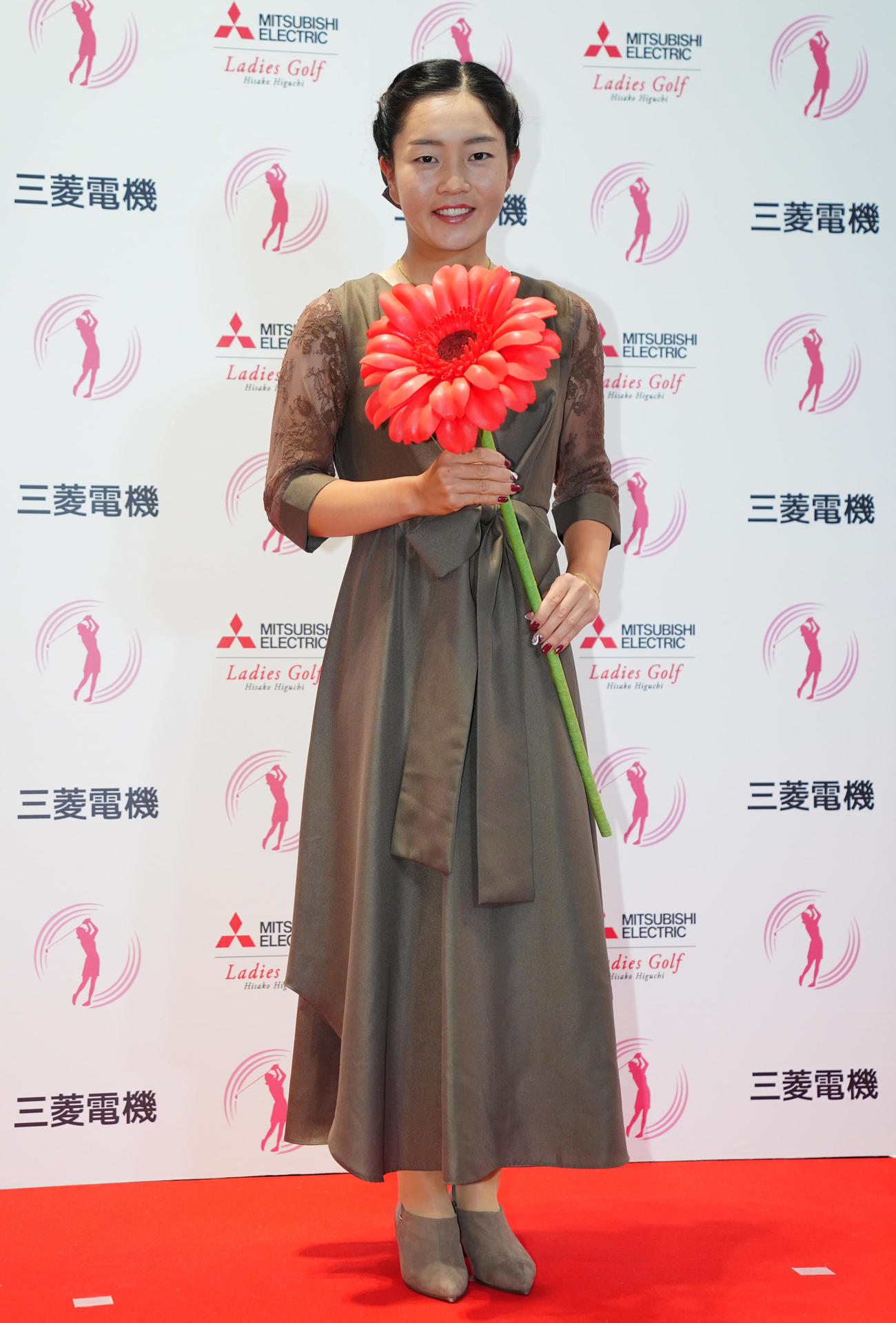ガーベラを手に写真に納まる佐藤（撮影・垰建太）