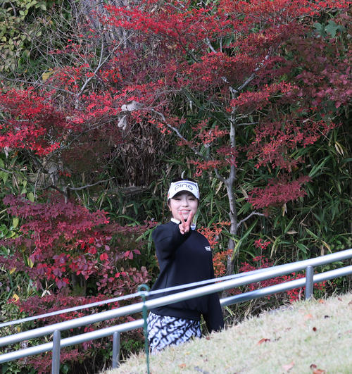 9番、グリーンを終えVサインで紅葉した木の前を通過する佐久間（撮影・加藤哉）