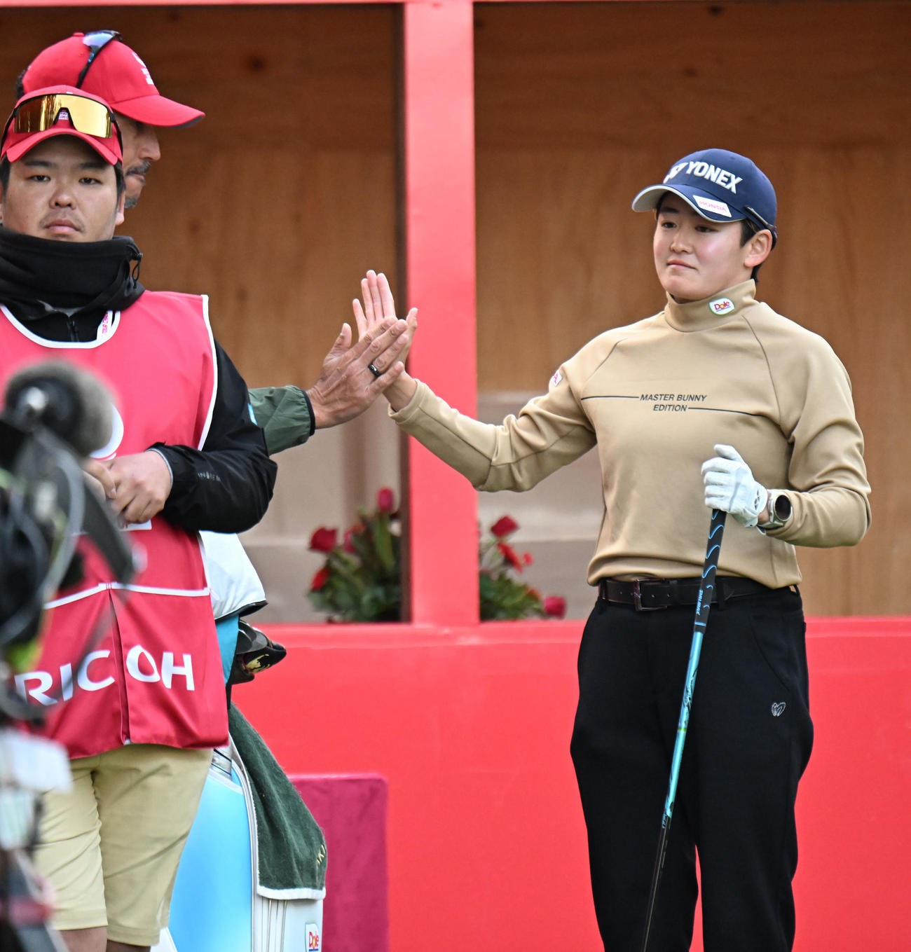 1番、キャディーとタッチをかわす岩井明愛（撮影・和賀正仁）