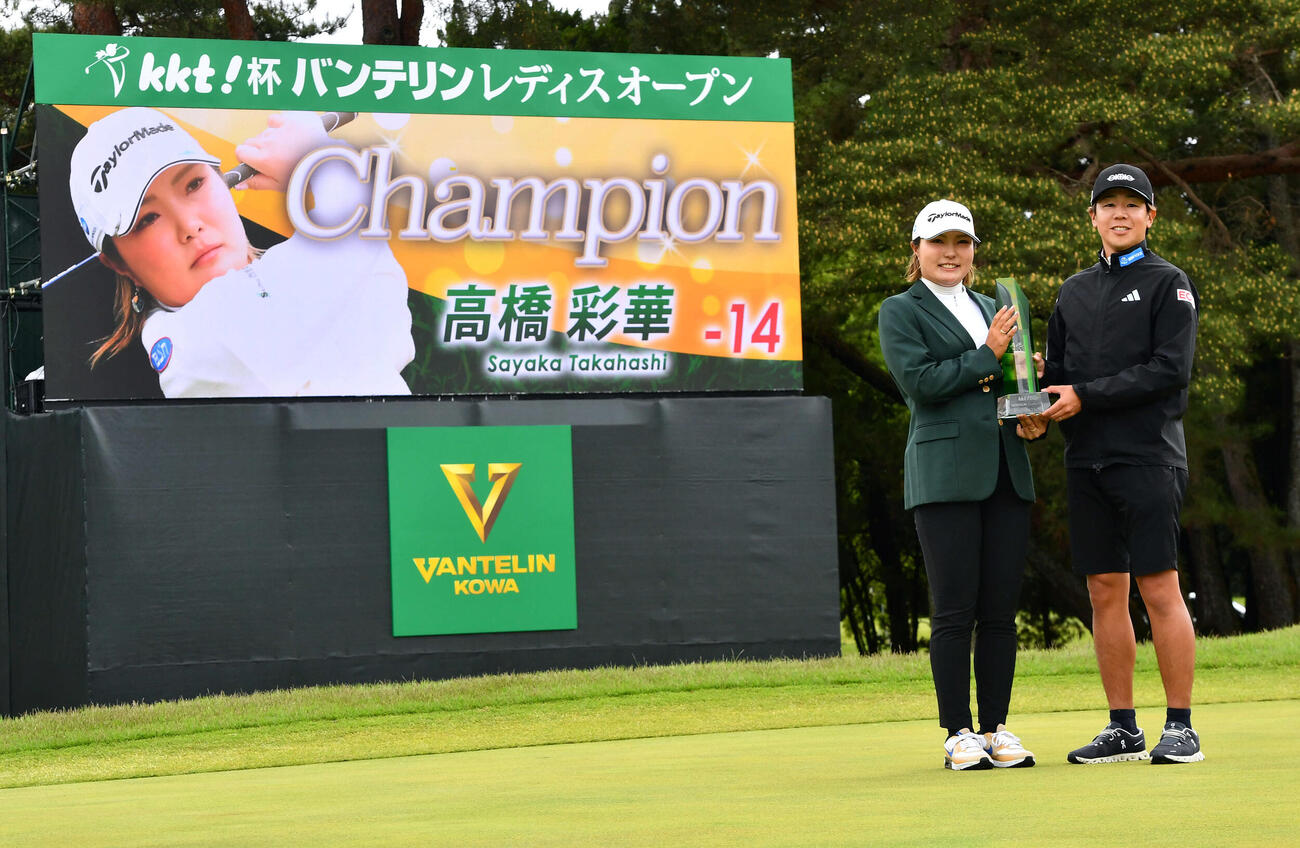 通算14アンダーで優勝した高橋彩華（左）は野村拓矢キャディーと一緒にトロフィーを手にする（撮影・岩下翔太）