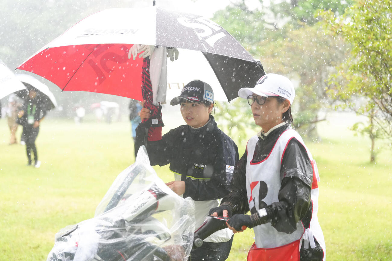 降雨によるコースコンディション不良のため競技が一時中断し、クラブハウスへと戻る尾関彩美悠（左）（撮影・足立雅史）
