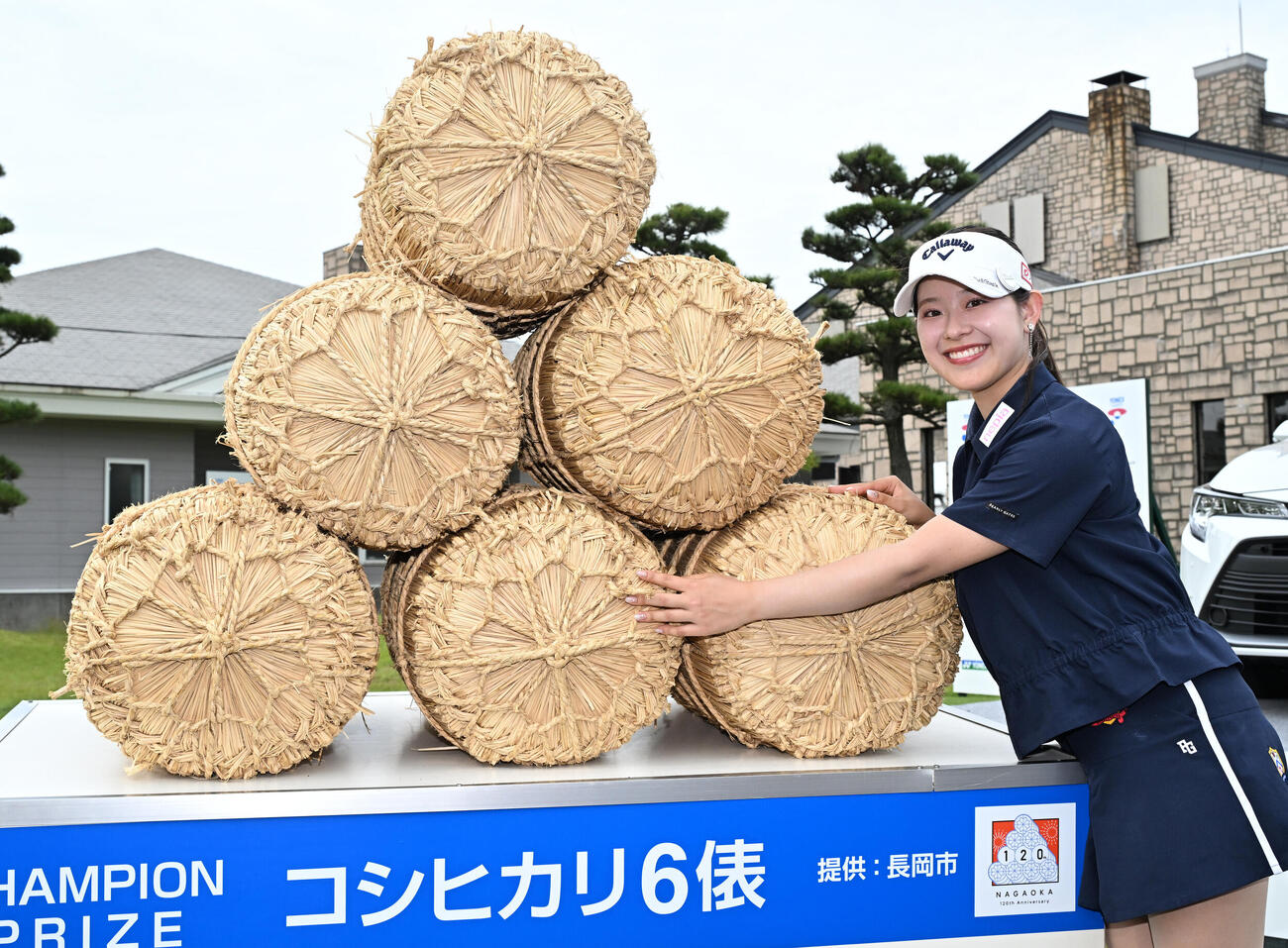 通算8アンダーで初優勝し、副賞の米俵の前でポーズをとる吉田鈴（撮影・千葉一成）
