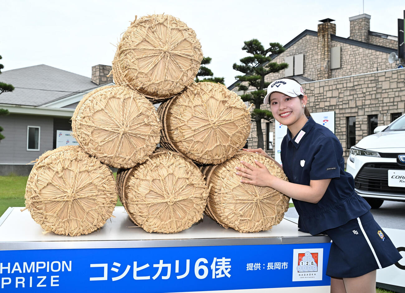 通算8アンダーで初優勝し、副賞の米俵の前でポーズをとる吉田鈴（撮影・千葉一成）