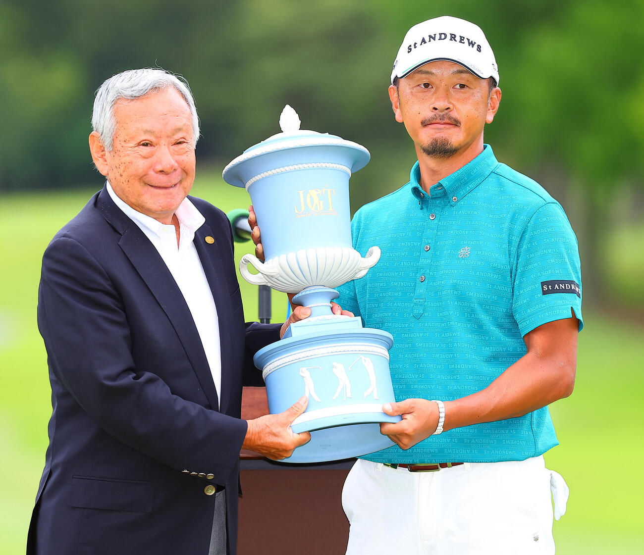 BMW日本ツアー選手権森ビル杯　優勝しJGTO諸星裕会長（左）から選手権杯を贈られる岩田寛（撮影・野上伸悟）