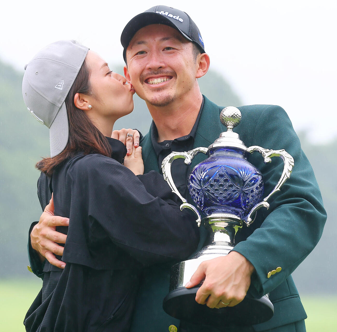 優勝し、真衣夫人（左）からキスで祝福される岩崎亜久竜（撮影・野上伸悟）