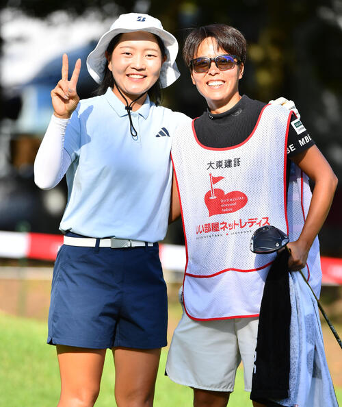10番、キャディーと肩を組んでピースサインを見せる佐藤心結（撮影・岩下翔太）