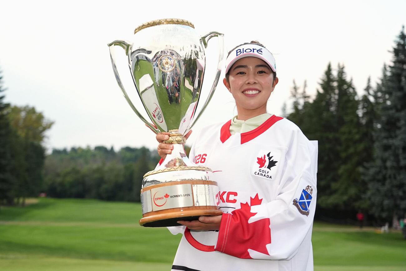 ホッケーのユニホームを着て優勝トロフィーを掲げる山下美夢有＝ロイヤル・メイフェアGC（共同）