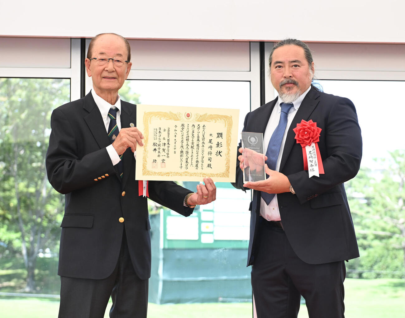 プレーヤー部門で故尾崎将司氏の殿堂入りが顕彰され、松井功エグゼクティブプレジデント（左）からトロフィーを贈られる長男・尾崎智春氏（撮影・和賀正仁）