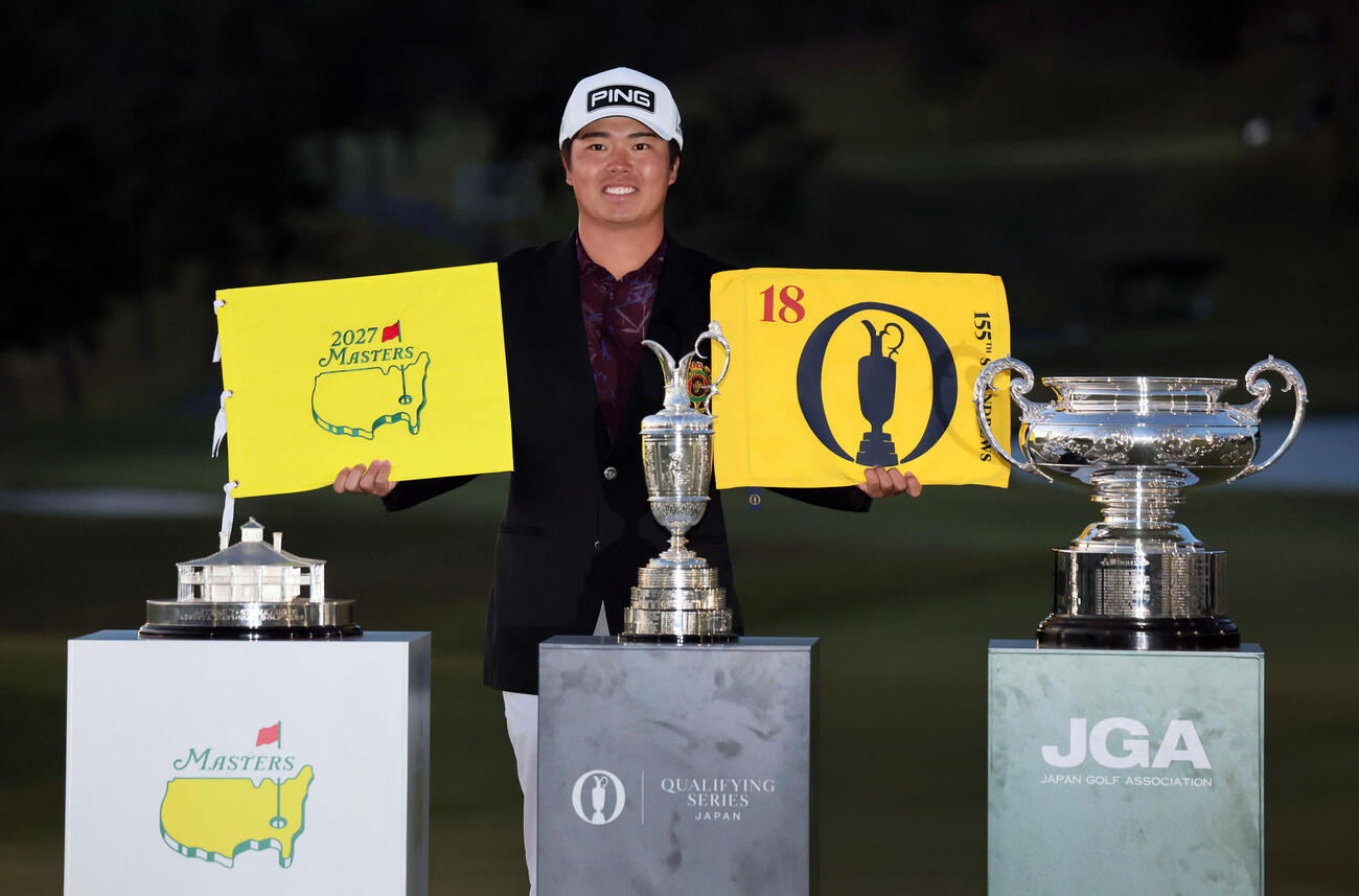 日本オープンゴルフで優勝した細野勇策は、米マスターズと全英オープンの出場権を獲得し、フラッグを手に優勝カップを前に笑顔を見せる（撮影・宮崎幸一）