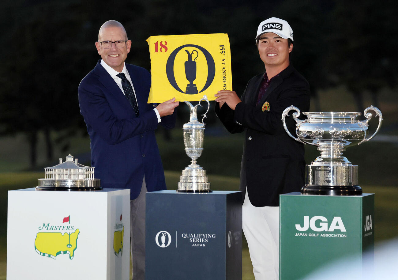 日本オープンゴルフで優勝した細野勇策（右）は、米マスターズと全英オープンの出場権を獲得し、R＆Aチーフグローバルゴルフアライアンスオフィサーのグラント・モイヤー氏と全英オープンのフラッグを手に笑顔を見せる（撮影・宮崎幸一）
