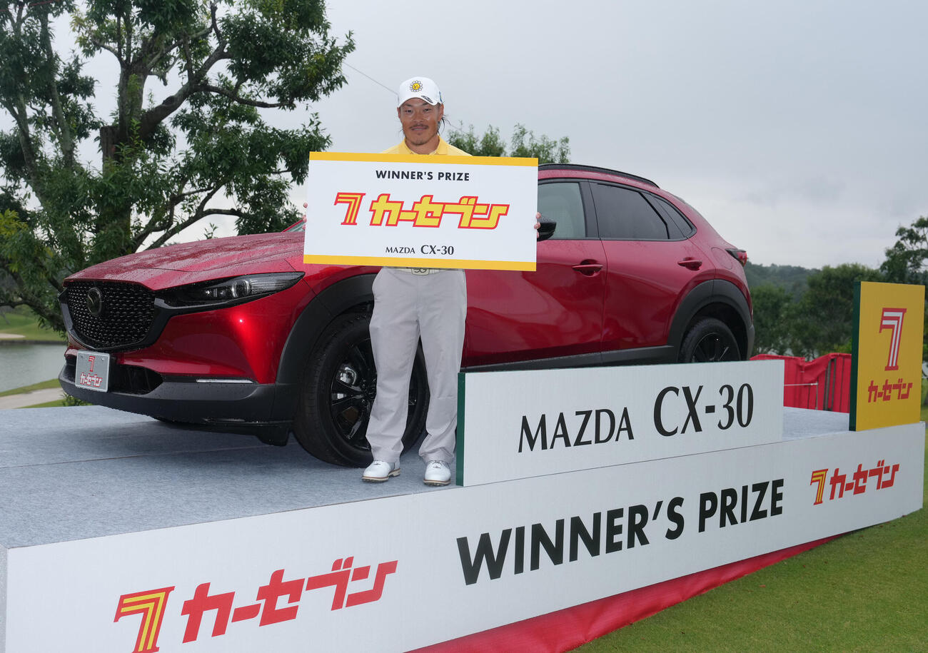 優勝賞品の車の前で笑顔を見せる藤本佳則（撮影・足立雅史）