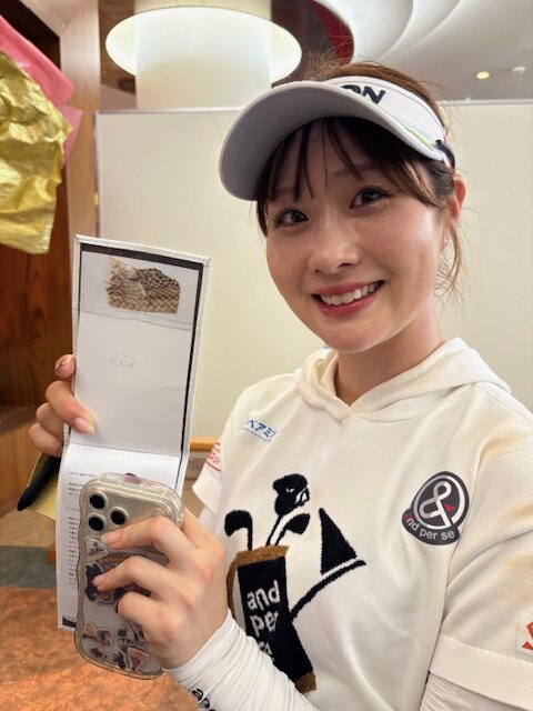 ヤーデージブックに貼り付けた蛇の抜け殻を見せる都玲華（26年10月24日撮影）