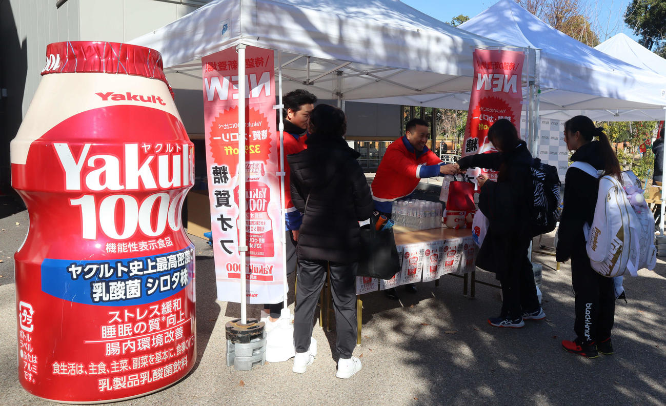 ヤクルトブースで新商品を渡される選手