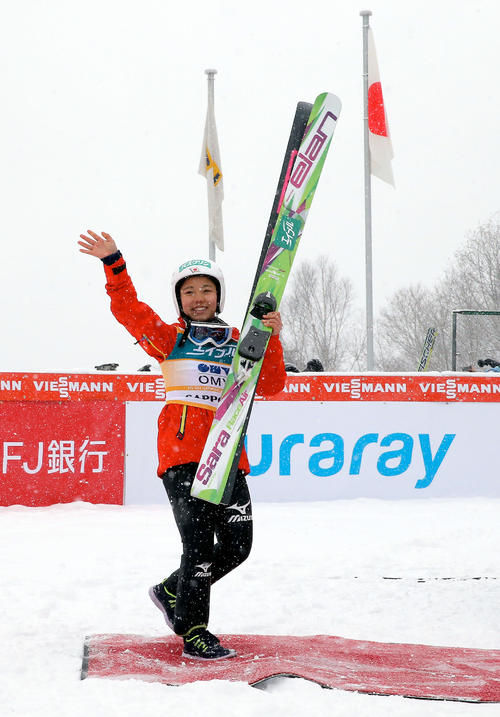 ２連勝で１５勝目を挙げた高梨は、日の丸を背にファンに向かって手を振る（１４年１月１２日）（撮影・井上学）