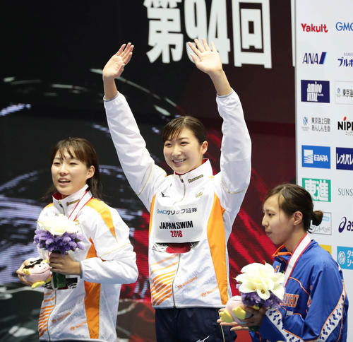 女子５０メートル自由形を日本新記録で制して声援に応える池江（中央）。左は２位の山本、右は３位の佐藤（撮影・丹羽敏通）