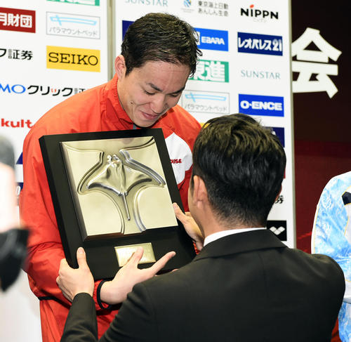 優勝した小関は表彰式で北島氏（背中）から北島康介杯を受け取る（撮影・滝沢徹郎）
