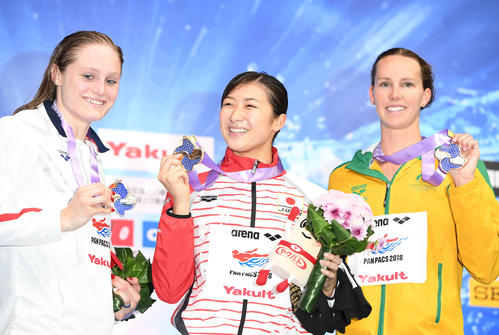 女子１００メートルバタフライ　金メダルの池江（中央）は笑顔でメダルを掲げる（撮影・山崎安昭）