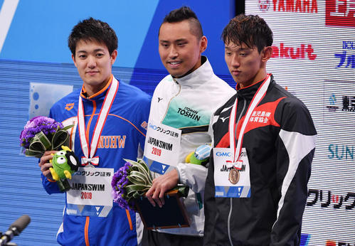 男子50メートル自由型で優勝し記念撮影する塩浦（中央）。左は2位の松井。右は3位の坂井（撮影・滝沢徹郎）
