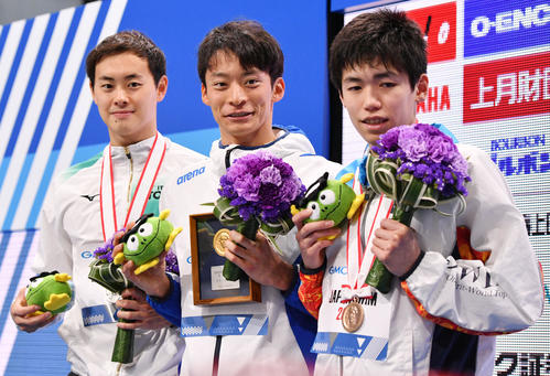 男子50メートル背泳ぎで優勝し表彰式で記念撮影する入江（中央）。左は2位の金子。右は3位の松山（撮影・滝沢徹郎）