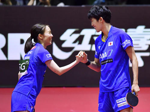 卓球世界選手権の混合ダブルスで決勝進出を決め、笑顔で握手する吉村真（右）、石川組＝25日、ブダペスト（共同）