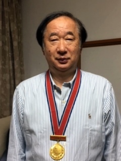 79年世界選手権個人戦の男子シングルスで獲得した金メダルを首からかける小野誠治さん