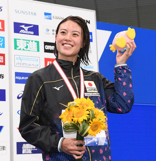 女子100メートル自由形で、400メートルリレーの派遣標準記録を突破した大本は笑顔で声援に応える（撮影・鈴木みどり）