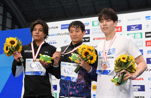 男子200メートル背泳ぎで優勝した入江（中央）は表彰台で笑顔。左は2位の江戸、右は3位のイ・ジュホ（撮影・鈴木みどり）