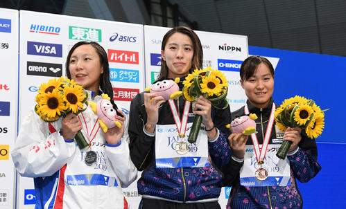 女子100メートルバタフライで優勝し、表彰台で笑顔の大橋（中央）。左は2位の相馬あい、右は3位の牧野紘子（撮影・鈴木みどり）