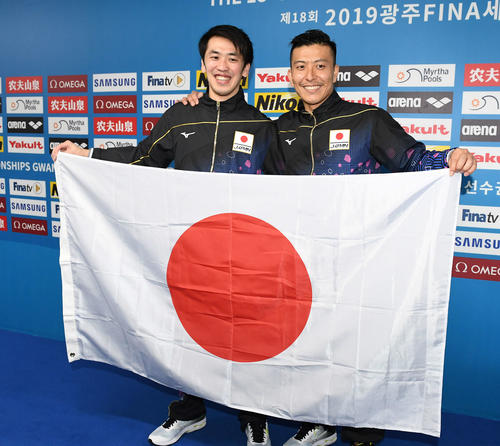 男子シンクロ板飛び込み決勝　「東京五輪内定1号」となり、笑顔で日の丸を広げる寺内（右）、坂井組（撮影・鈴木みどり）