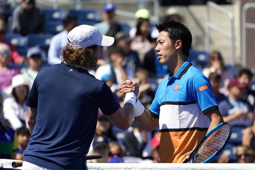 男子シングルス1回戦　途中棄権したマルコ・トルンヘリティ（左）と握手する錦織圭（共同）