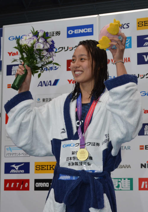 女子100メートル平泳ぎで優勝し、応援席に手を挙げる今井月（撮影・吉池彰）
