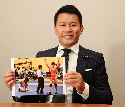 レスリング男子フリースタイル65キロ級の乙黒拓斗の写真を手にする須藤元気氏（撮影・丹羽敏通）