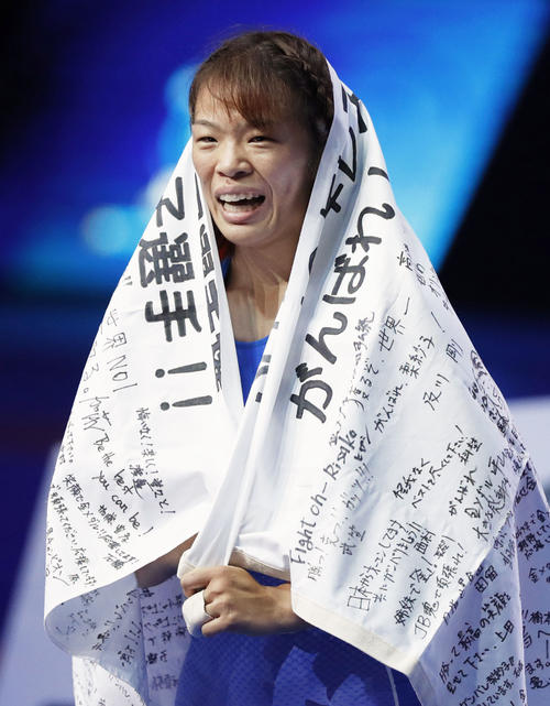 女子57 キロ 級で優勝し、多くのメッセージが書かれた日の丸をまとう川井梨紗子（共同）