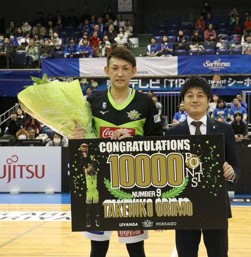 19年、1万点記念ボードを手にする北海道折茂武彦選手兼社長（左）