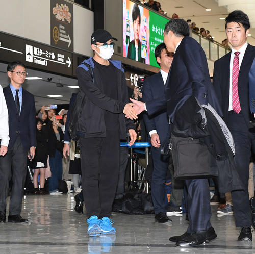 マレーシアから帰国した桃田（左）は日本バドミントン協会の銭谷専務理事（中央）と握手を交わす（2020年1月15日）