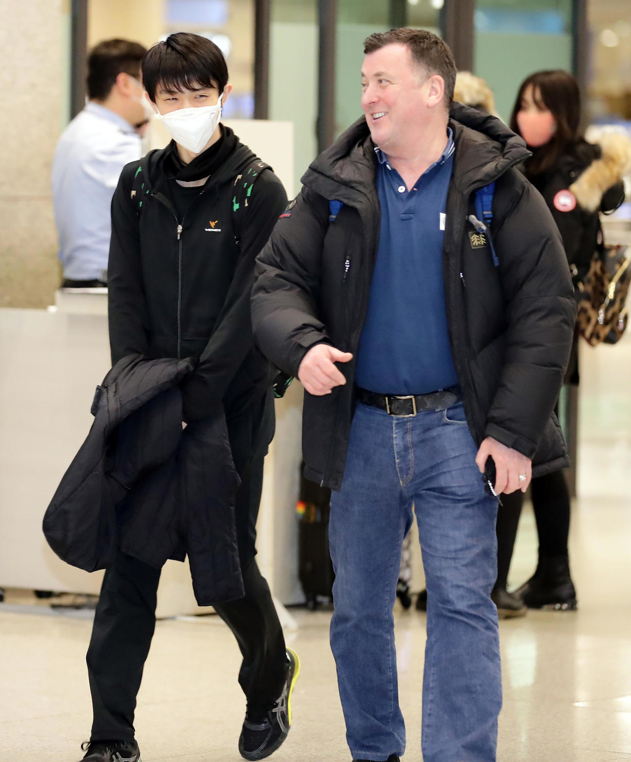 マスク姿でオーサーコーチ（右）と談笑しながら韓国の仁川国際空港に到着した羽生（撮影・浅見桂子）