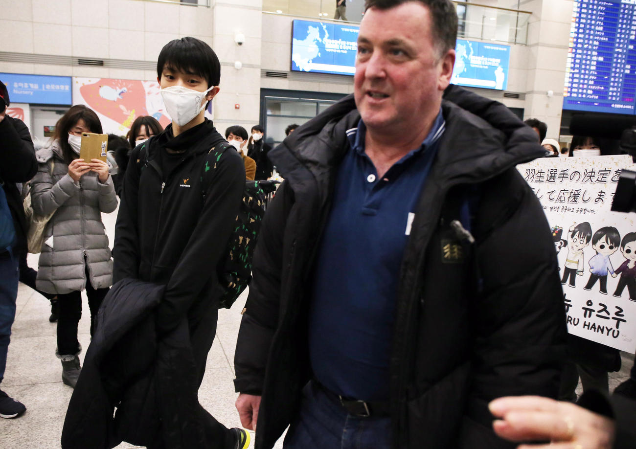 韓国の仁川国際空港に到着した羽生（左）は横断幕を持つファンの前を通り過ぎる（撮影・浅見桂子）