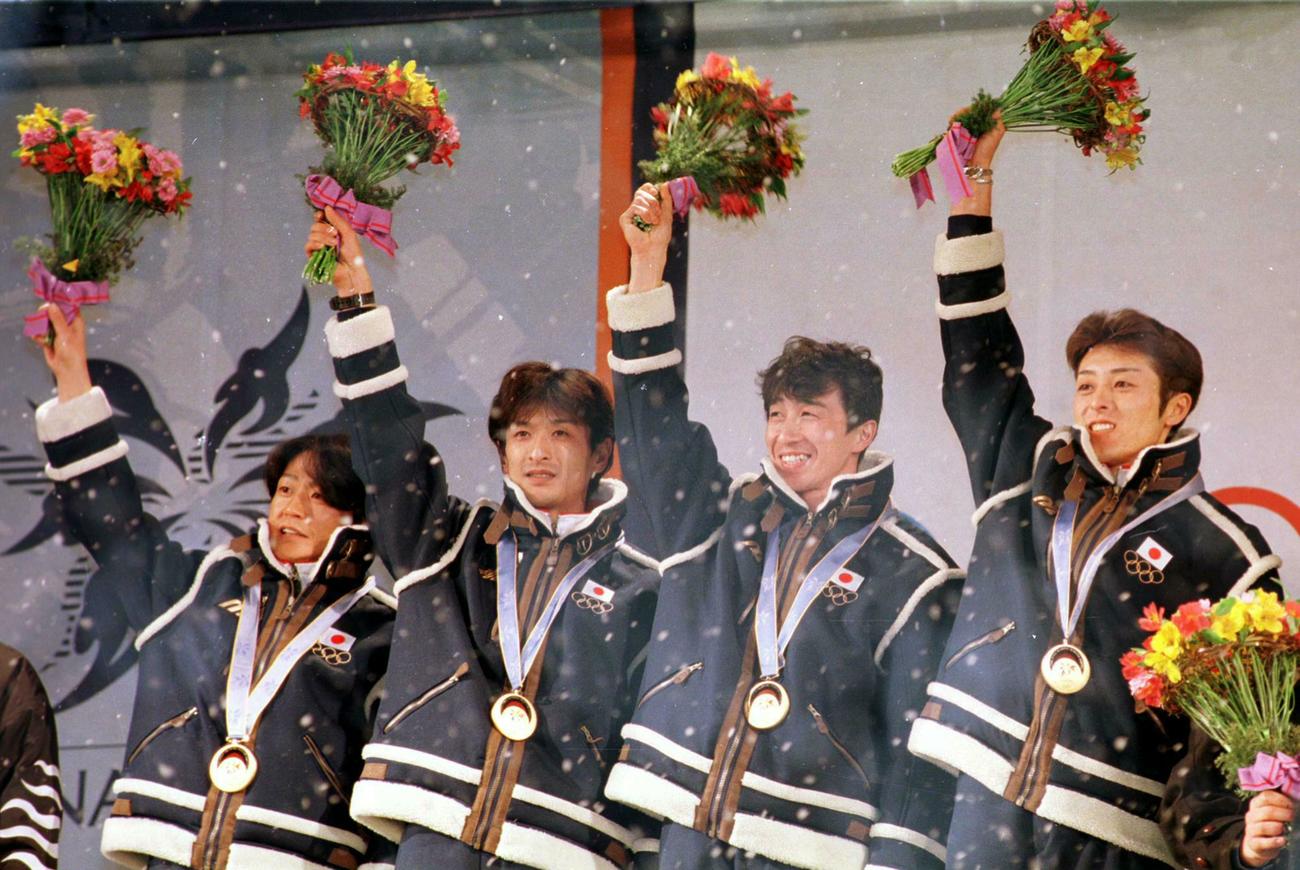 長野五輪ジャンプ団体で金メダルを獲得しフラワーセレモニーで笑顔の（左から）岡部孝信、斎藤浩哉、原田雅彦、船木和喜（1998年2月17日撮影）