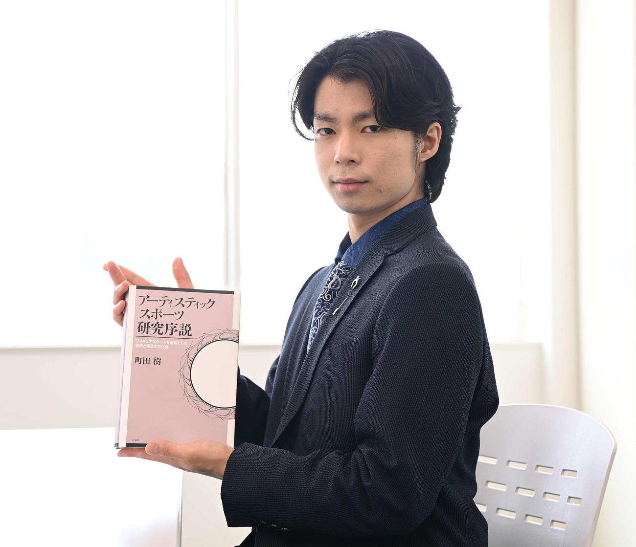 著書「アーティスティックスポーツ研究序説」を手に写真に納まる町田樹氏（撮影・鈴木みどり）