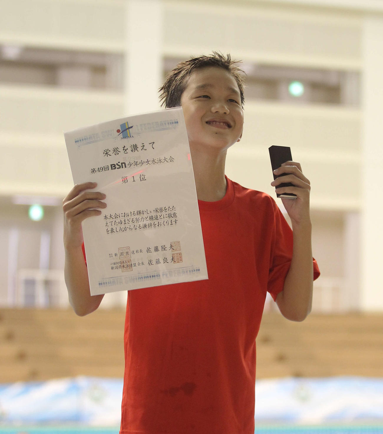 表彰台の根岸はうれしさ半分のニッコリ顔